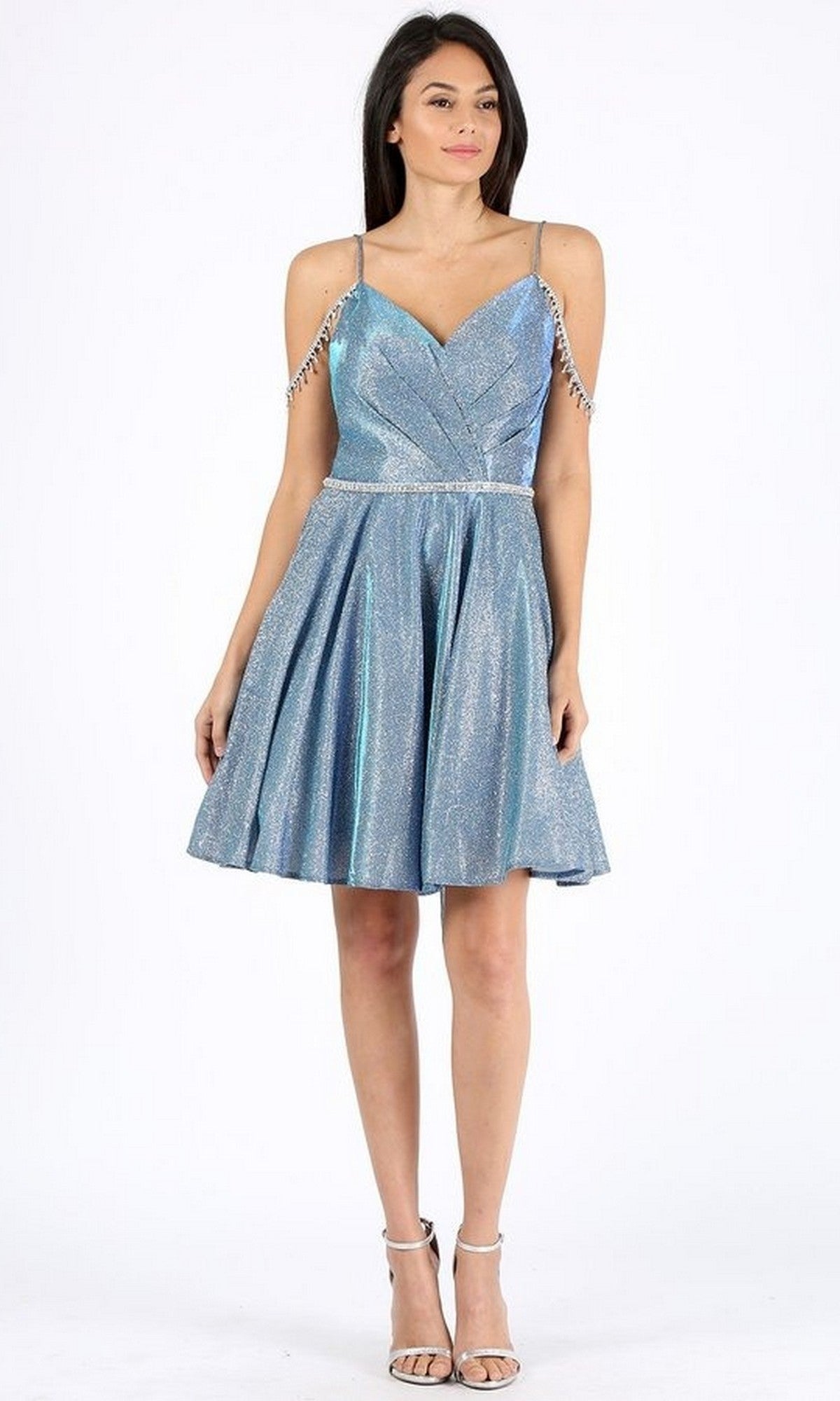A woman models the Short Prom Dress: Eureka 9722 in Periblue—a glitter-jersey fit-and-flare cocktail dress with thin straps and v-neckline—paired with silver open-toe heels against a plain white background.